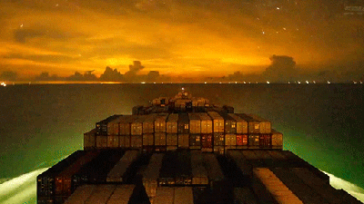 A Container Ship Travelling Around The Ocean At Night Is One Of The Most Beautiful Things