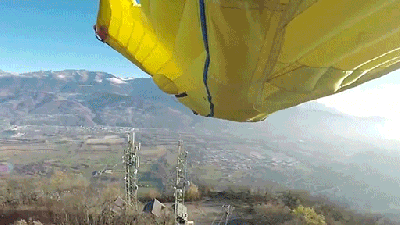Man In Wingsuit Flies Through A Narrow Opening Between Two Antennas