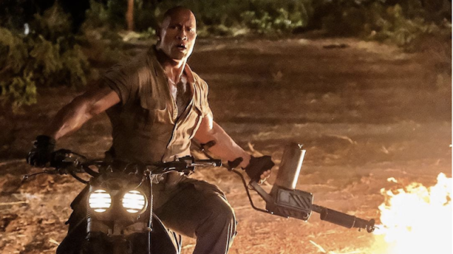 Here’s A Photo Of The Rock Wielding A Flamethrower While Riding A Motorcycle On The Jumanji Set