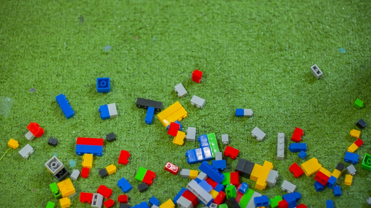 Colored toy bricks with place on green ground very messy.