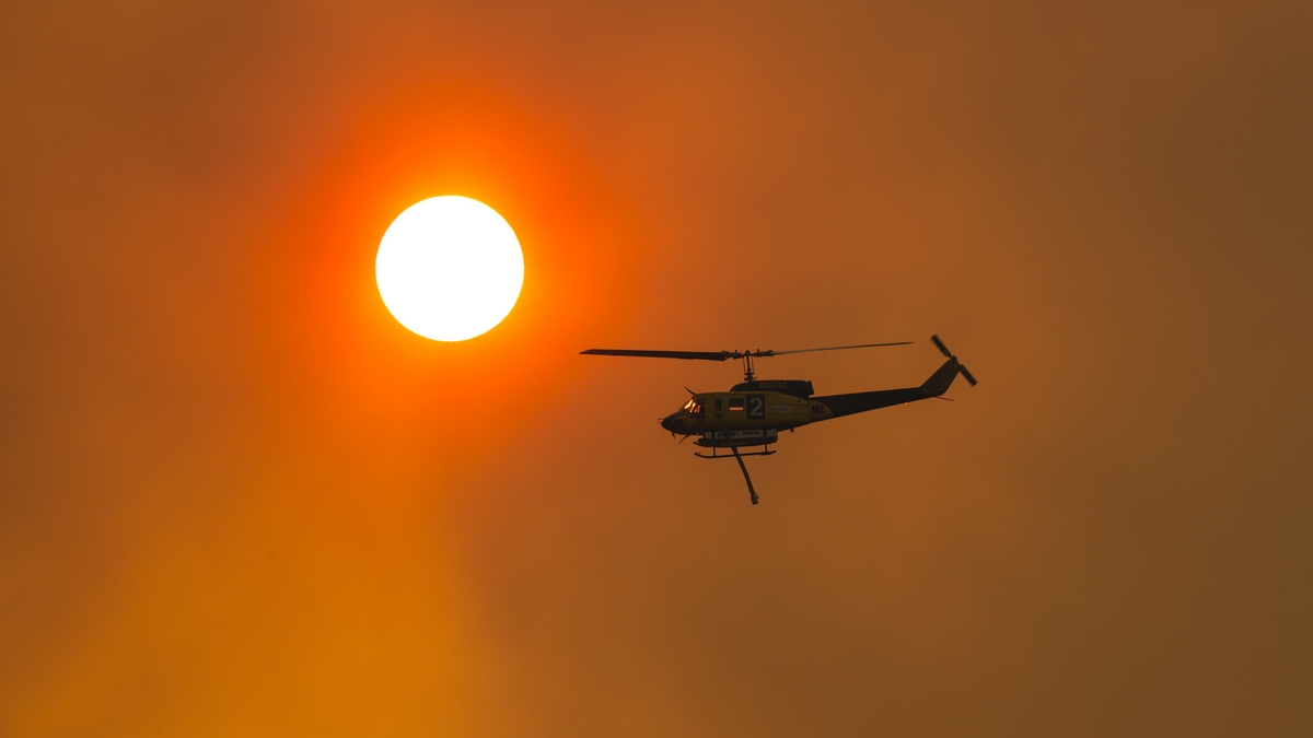 Water bombing helicopters working into the sunset to try and contain a large fire