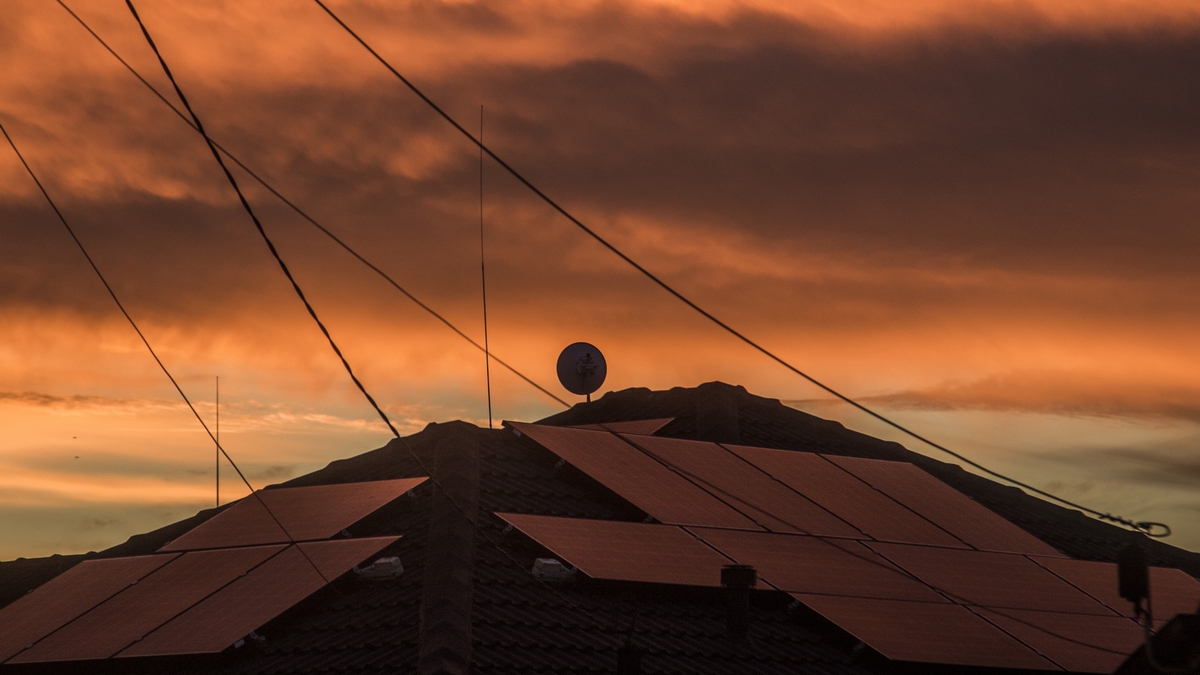 Solar panels on rooftop under dramatic sky at sunrise