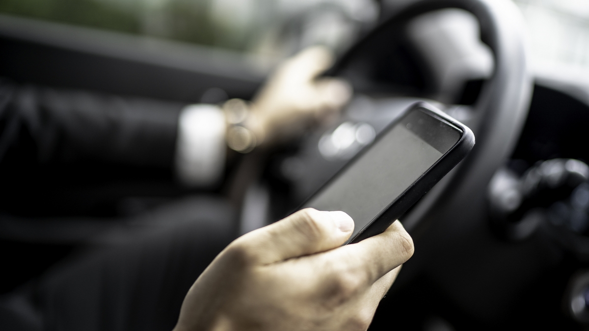 Man texting while driving car