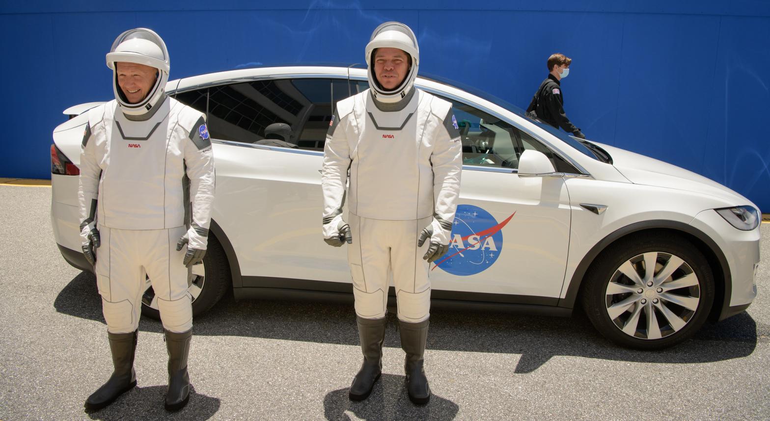 NASA astronauts Douglas Hurley and Robert Behnken wearing SpaceX spacesuits and with a Tesla Model X behind them.  (Image: NASA)