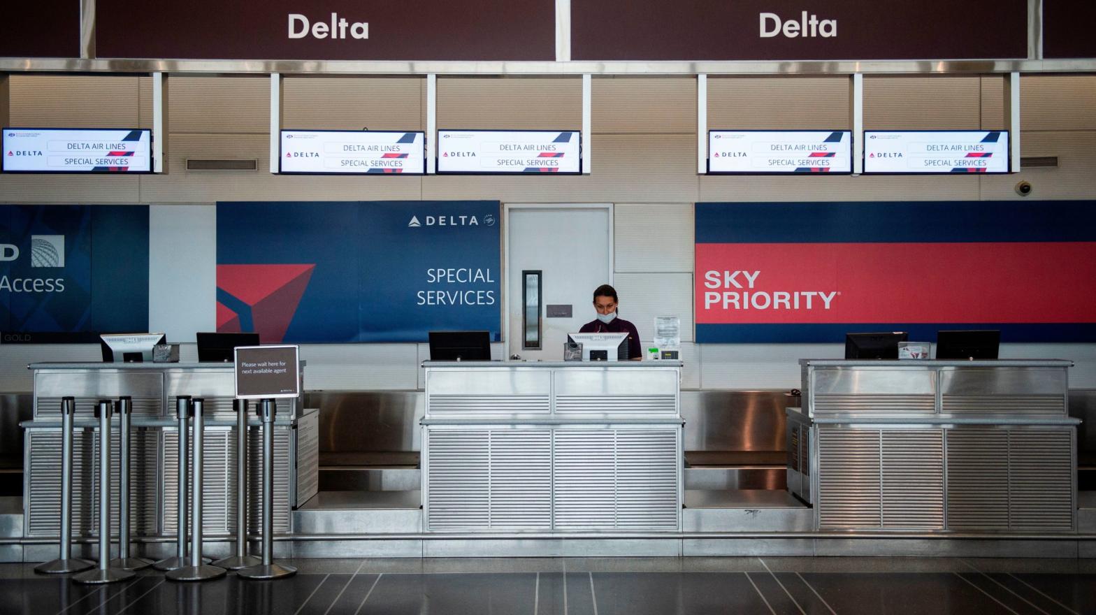 A Delta airlines employee waits for passengers at an empty check-in counter in Ronald Reagan Washington National Airport in Arlington, Virginia, on May 12, 2020. (Photo: Getty Images)
