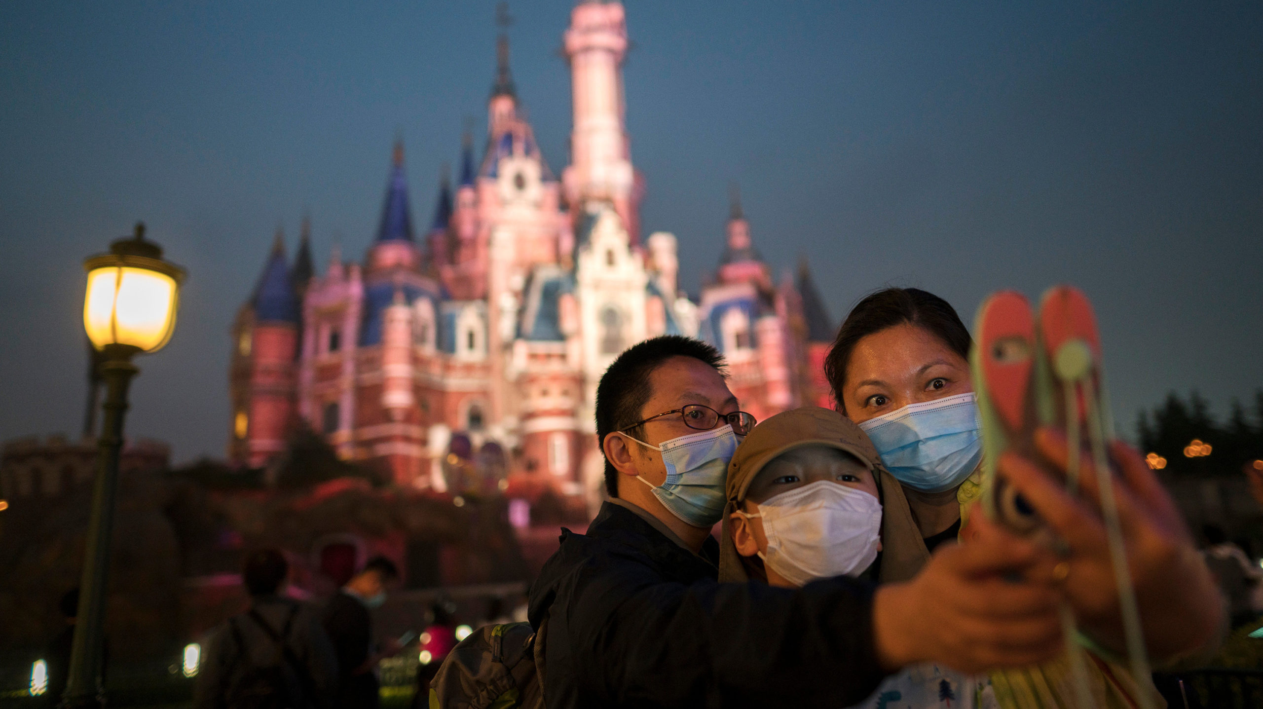 Guests take a photo in Shanghai Disneyland, a park where mask mandates have been largely successful. (Photo: Hu Chengwei , Getty Images)