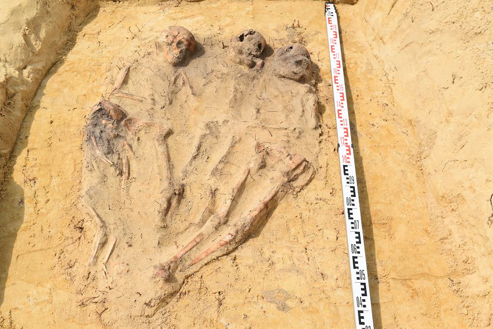 A grave containing four children, laid side-by-side, with legs and feet meeting together.  (Image: Arkadia Firma Archeologiczna/Facebook)