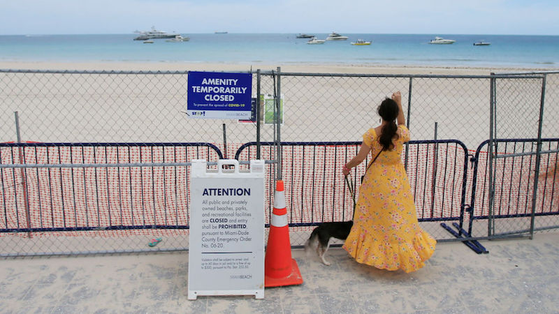 Miami Beach, Florida on July 4, 2020. A woman looks through the fence towards the beach. Miami-Dade County temporarily closed beaches over 4th of July weekend and imposed a curfew. (Photo: Cliff Hawkins, Getty Images)