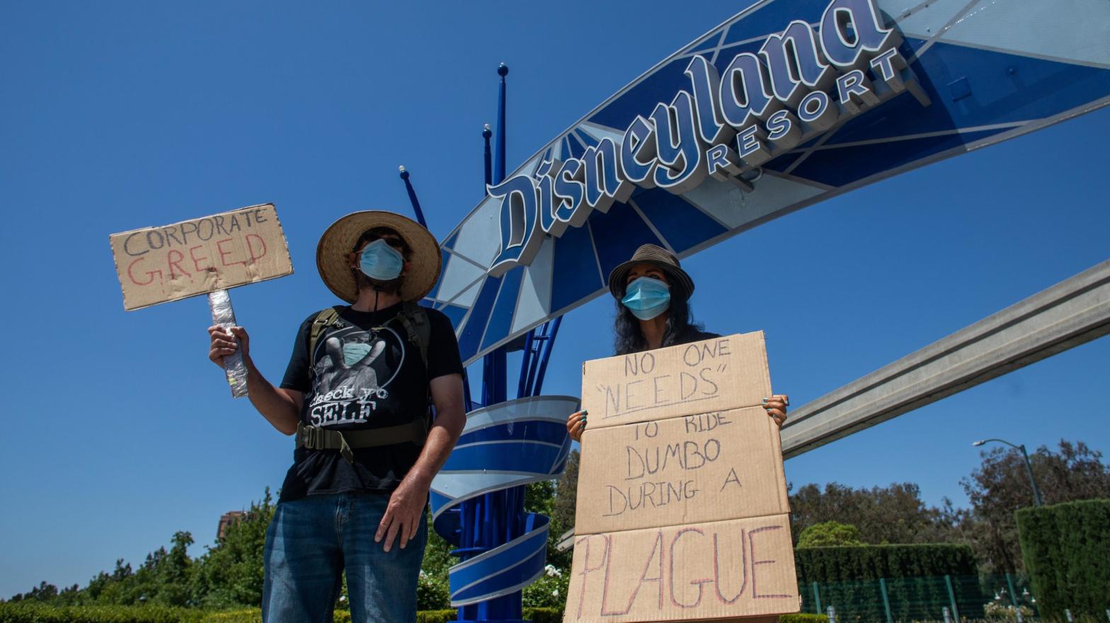 People holding signs in front of Anaheim's Disneyland as part of a cast member unions protest against reopening without on-demand covid-19 testing.  (Photo: Apu Gomes/AFP, Getty Images)