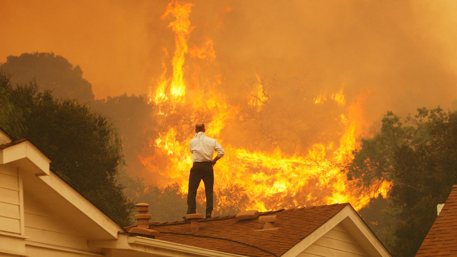 A man on a rooftop looks at approaching flames from the Springs fire in May 2013 near Camarillo, California.  (Photo: David McNew, Getty Images)