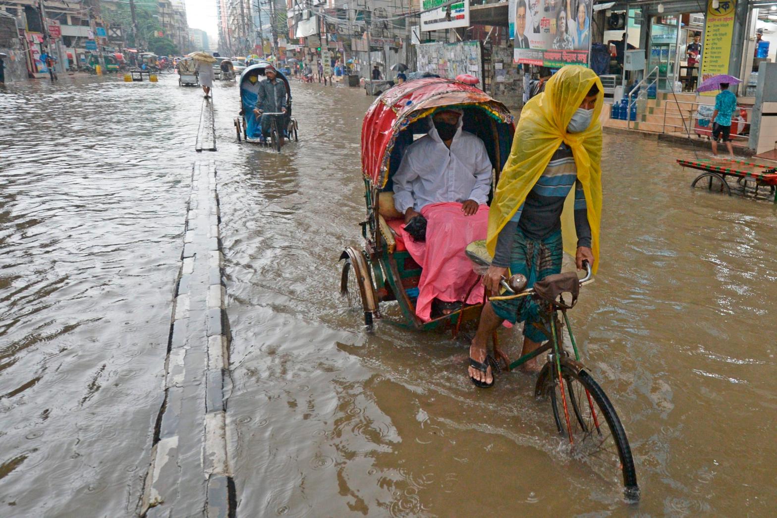 Rickshaw pullers make their way through a water-logged street after a heavy downpour in Dhaka on June 21, 2020. (Photo: Munir Uz Zaman, Getty Images)
