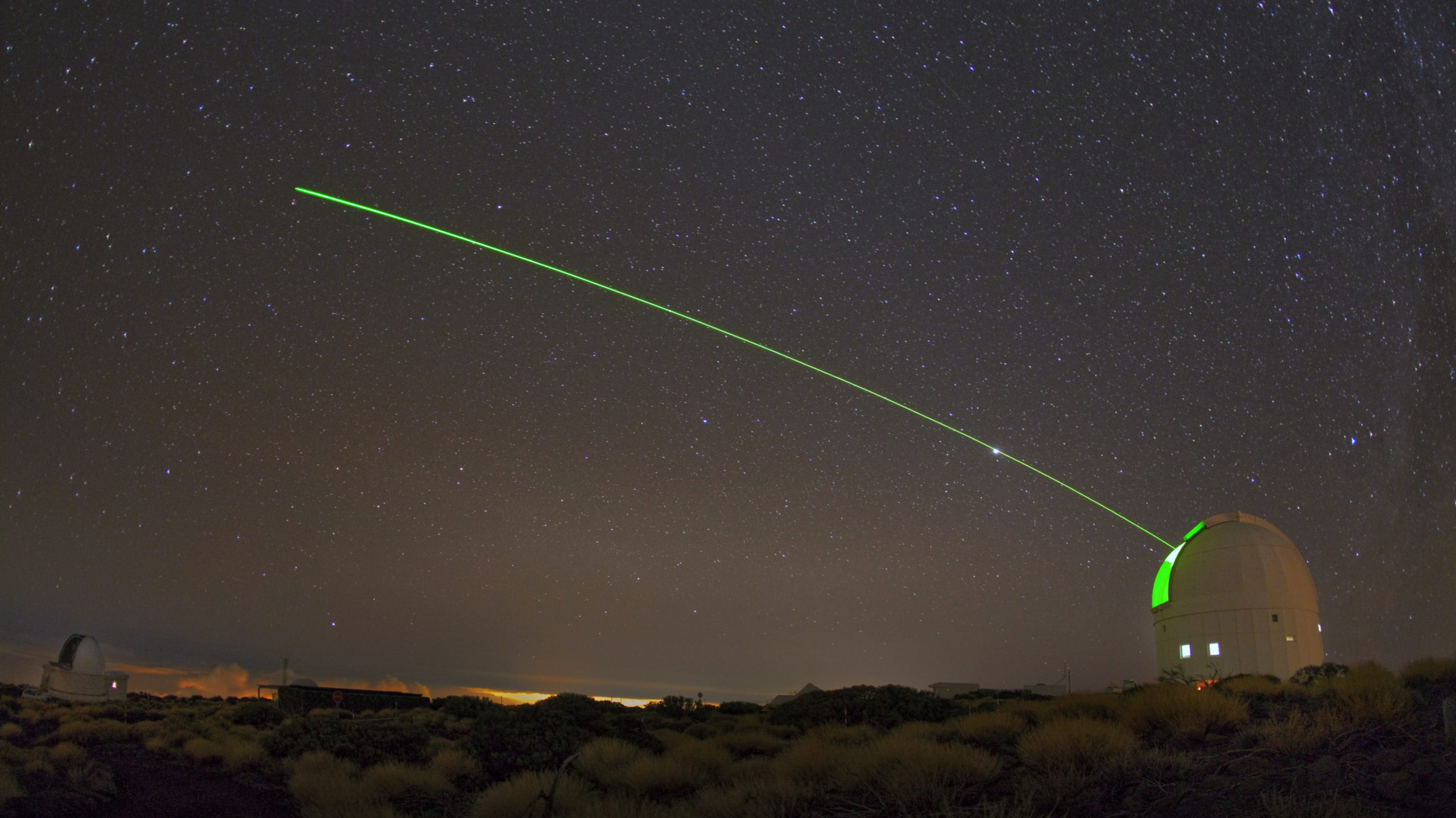 A visible green laser shines from ESA's Optical Ground Station (OGS). (Image: IAC– Daniel López)