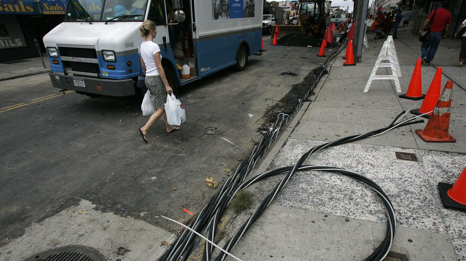 A woman walks past power lines on the footpath as workers try to restore electrical service July 23, 2006 in the Queens borough of New York City.  (Photo: Chris Hondros, Getty Images)
