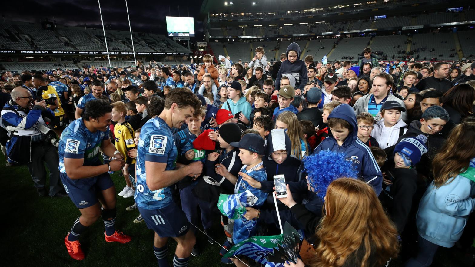Life returns to normal in New Zealand without need for social distancing, as a crowd comes onto the field to get player autographs during round 1 of the Super Rugby Aotearoa match between the Blues and the Hurricanes at Eden Park on June 14, 2020 in Auckland, New Zealand.  (Photo: Phil Walter, Getty Images)