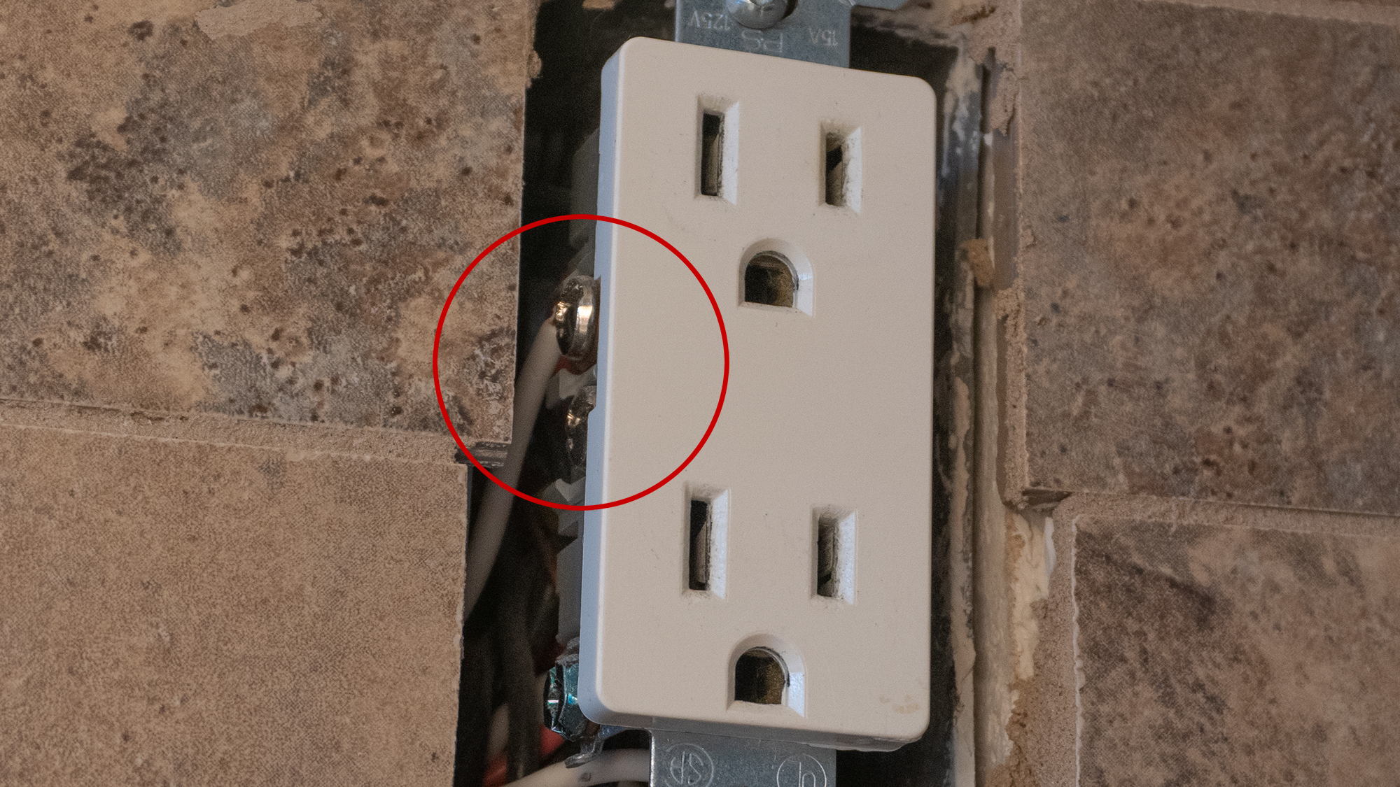 The prongs on the ConnectLight outlet cover make contact with these metal screws found on the sides of almost any outlet. (Photo: Andrew Liszewski/Gizmodo)