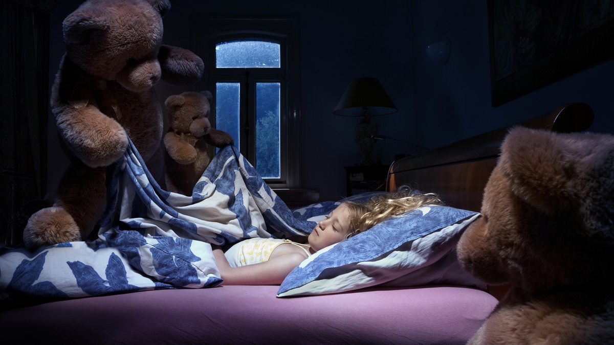 stock image Teddy bears tucking a girl into bed