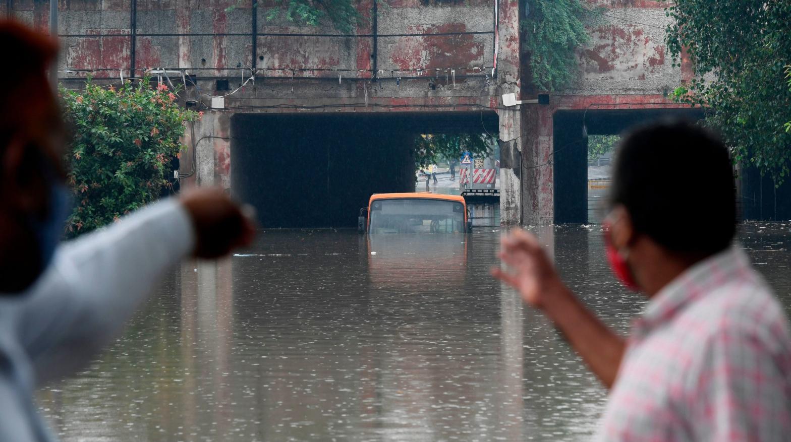 Local residents look at a submerged bus in a waterlogged road underpass after monsoon rainfalls in New Delhi (Photo: Prakash Singh, Getty Images)