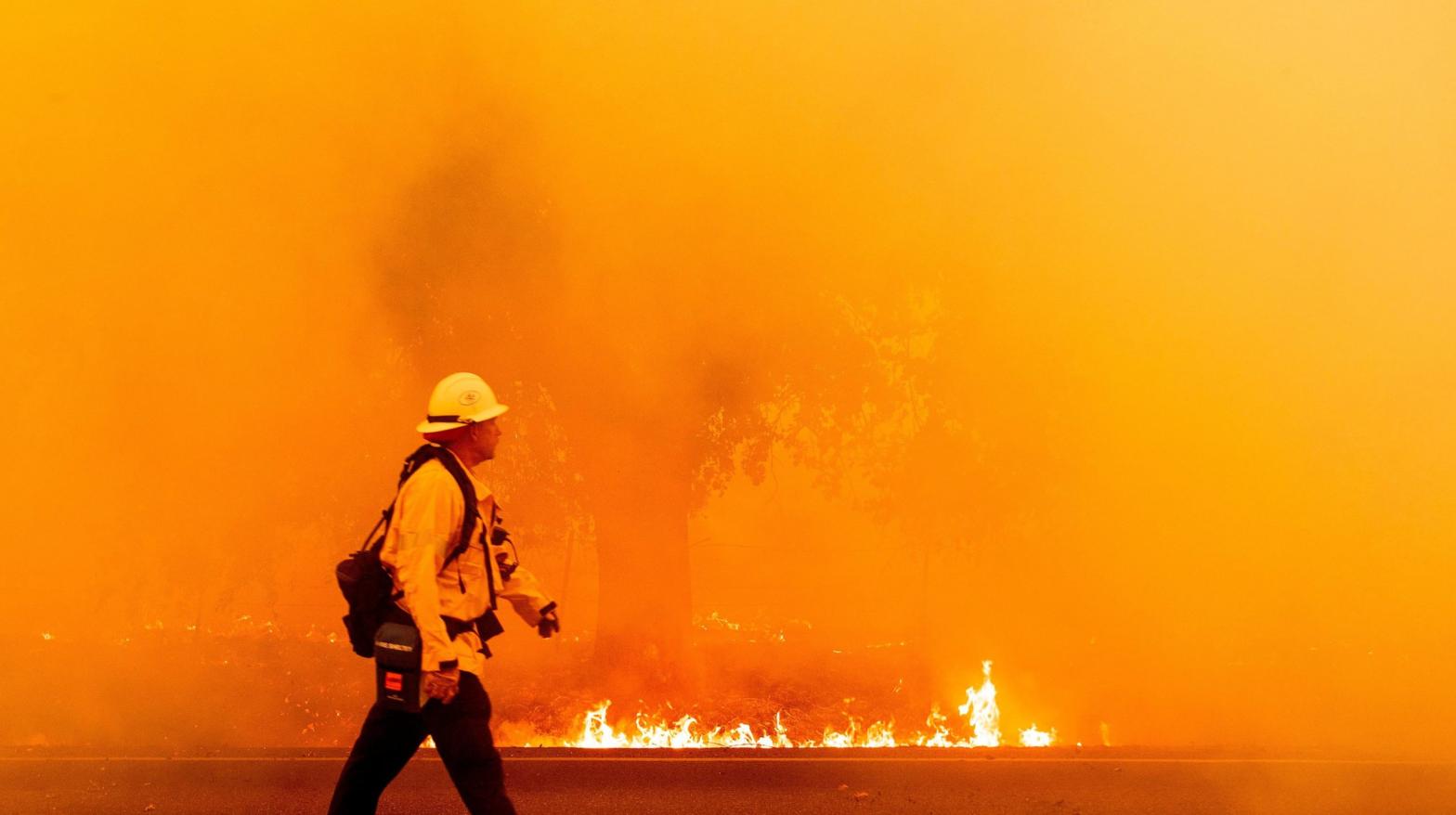 A firefighter walks in front of a blaze. (Photo: Josh Edelson, Getty Images)
