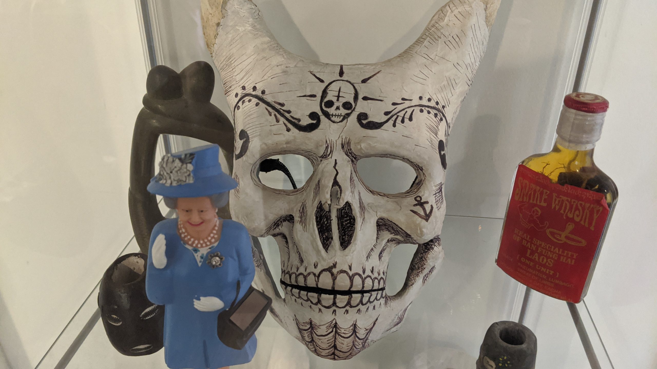 A demonic ritual mask, accompanied by a flask of potion and a smiling sculpture of an unknown fallen angel of some sort. (Photo: Tom McKay/Gizmodo, In-House Art)