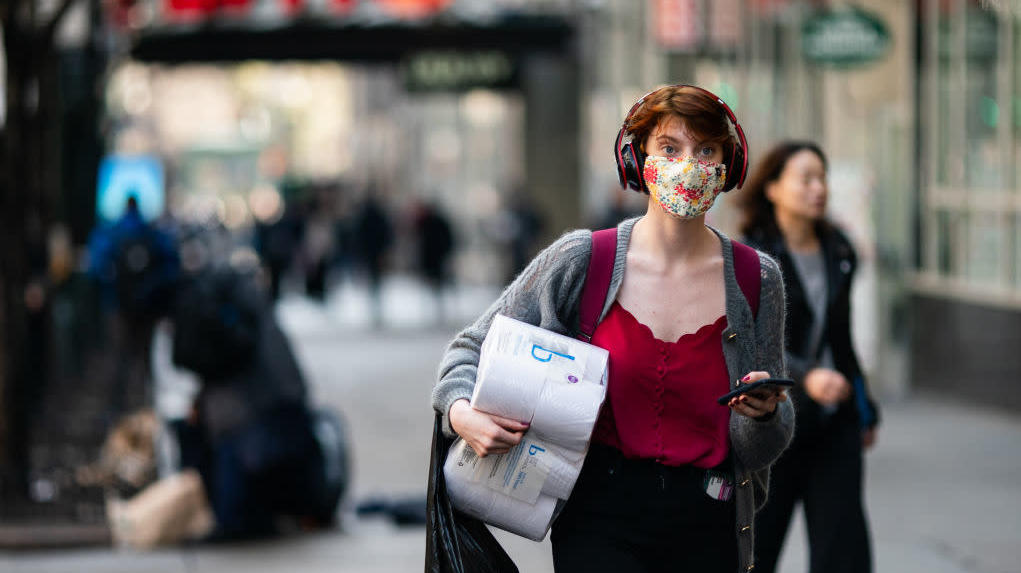 A woman wearing a protective mask carries a toilet paper package on the street on March 13, 2020, in New York City. (Photo: Jeenah Moon, Getty Images)