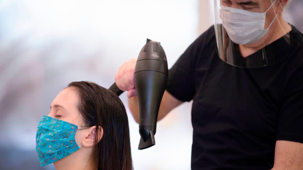 Stylist Neck Gunes (R) blow-dries his customer Jennifer Nardelli's hair while wearing a face mask and shield at Saint Germain Hair Salon in Washington, D.C., on May 29, 2020, (Photo: Jim Watson / AFP, Getty Images)