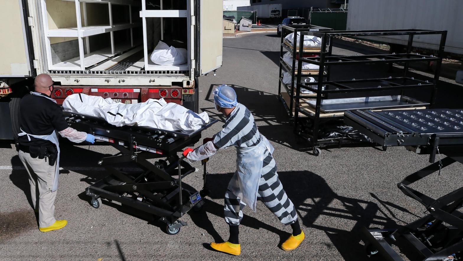 An inmate (centre) works loading bodies wrapped in plastic into a refrigerated temporary morgue trailer in a parking lot of the El Paso County Medical Examiner's office on November 17, 2020 in El Paso, Texas. (Photo: Mario Tama, Getty Images)