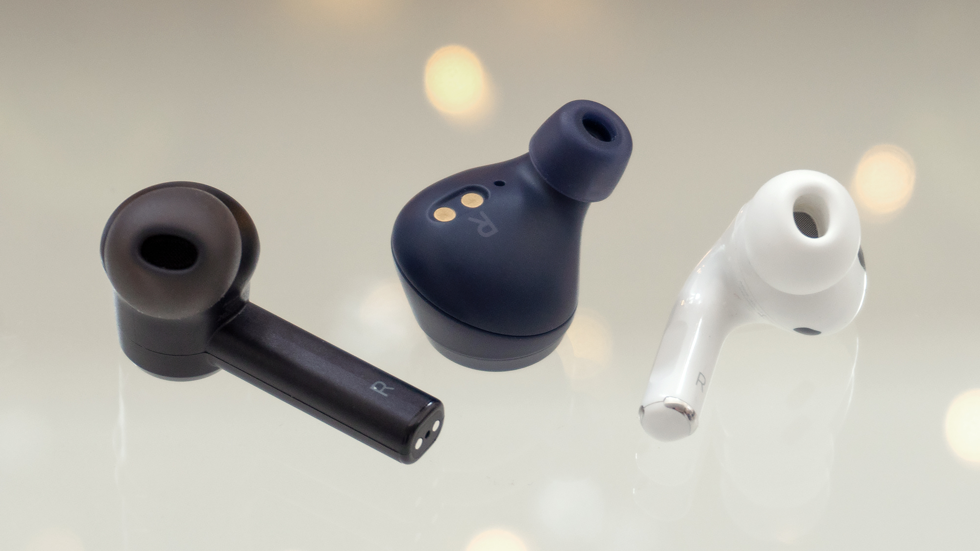 Razer's new Hammerhead True Wireless Pro (left) feature a design similar to the AirPods Pro (right) but a little larger to make room for impressive-sounding 10-millimetre drivers. Aside from the stem, they also don't stick out of your ears like the excellent Jabra Elite Active 75t (centre) tend to. (Photo: Andrew Liszewski / Gizmodo)