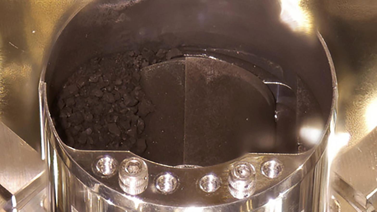 Dark pebbles and dust seen inside Hayabusa2's storage chamber.  (Image: JAXA)
