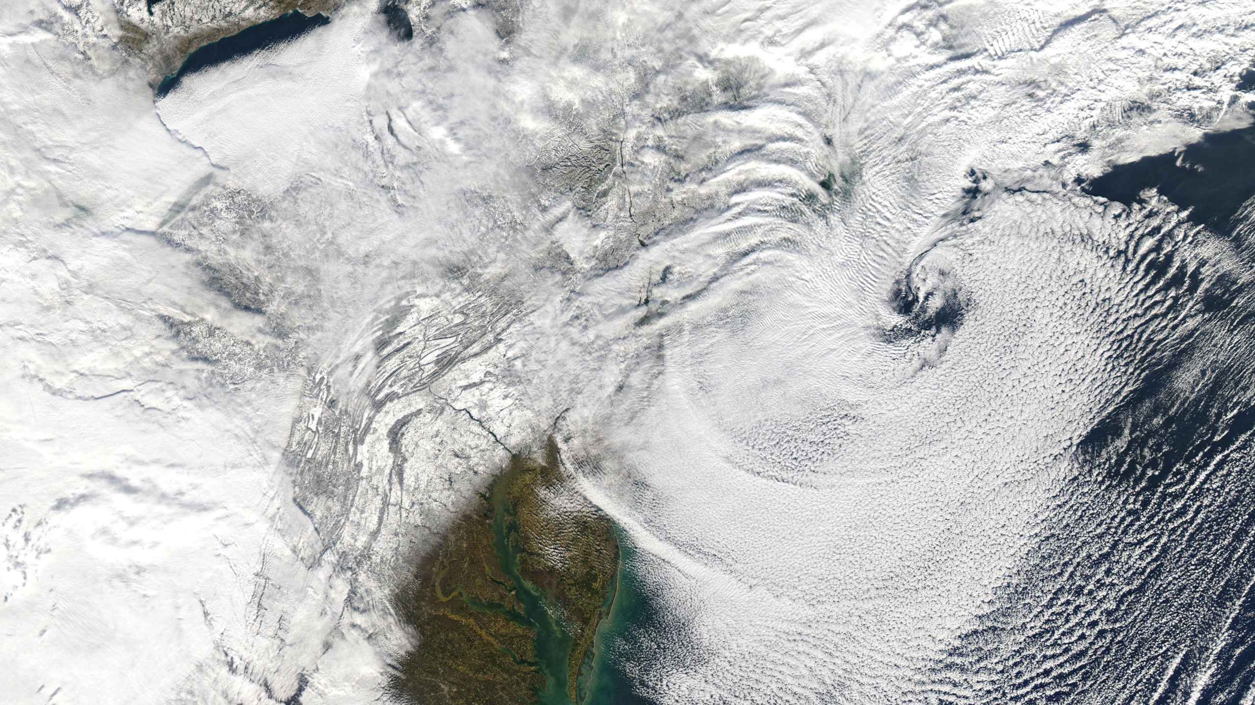 The swirling tail of the nor'easter moves further offshore, revealing the snow-blanketed Northeast on Dec. 17. (Image: NASA)