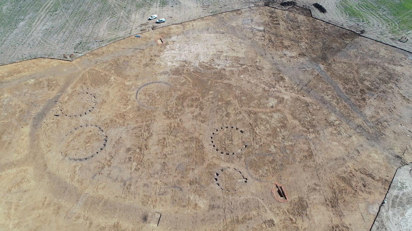 The footprints of some of the Iron Age roundhouses (vans at top for scale). (Photo: Oxford Archaeology East)