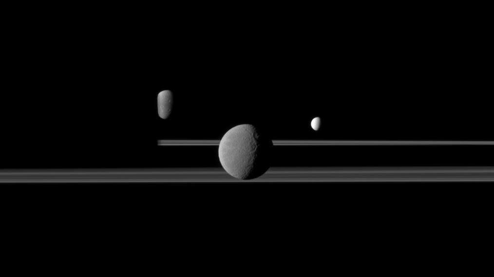Rhea seen in front of Saturn's rings. The moons Dione, left, and Enceladus, right, are in the background. (Image: NASA/JPL/Space Science Institute, Fair Use)
