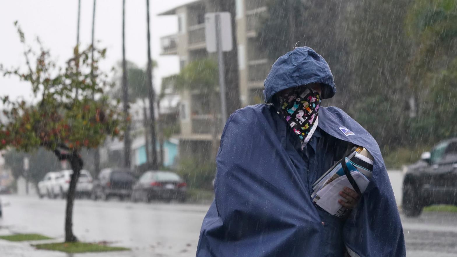 A Postal Service worker delivers mail in the rain in Long Beach, California. (Photo: Ashley Landis, AP)