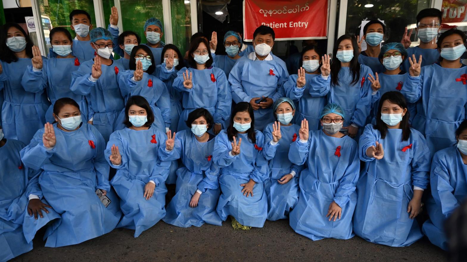 Medical staff makes a three finger salute with a red ribbons on their uniform at the Yangon General Hospital in Yangon on February 3, 2021. (Photo: STR/AFP, Getty Images)