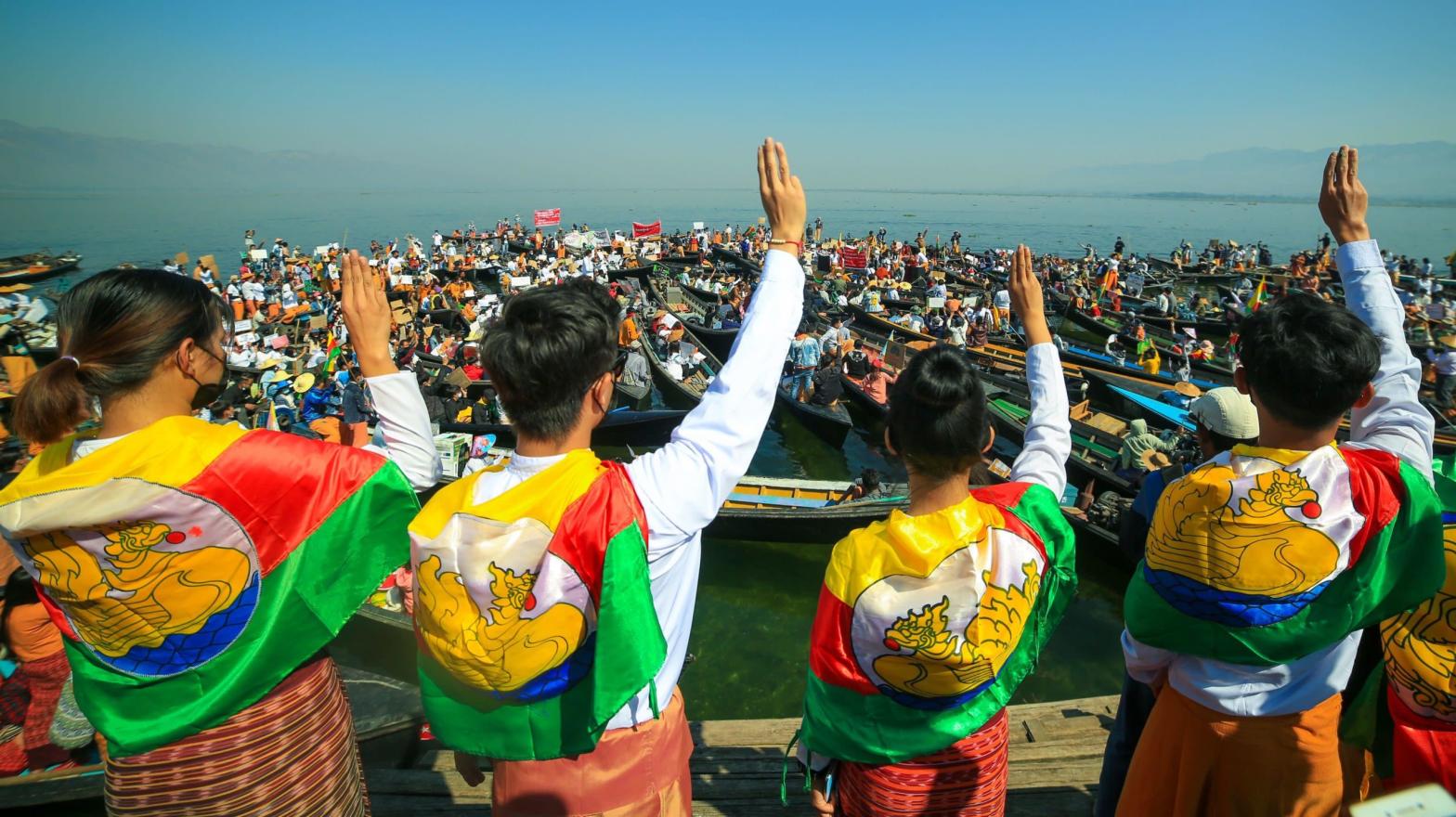 Protesters wearing traditional Shan dress make the three-figner salute as others hold signs during a demonstration against the Myanmar military coup in Inle Lake, Shan state on February 11, 2021. (Photo: Calito/AFP, Getty Images)