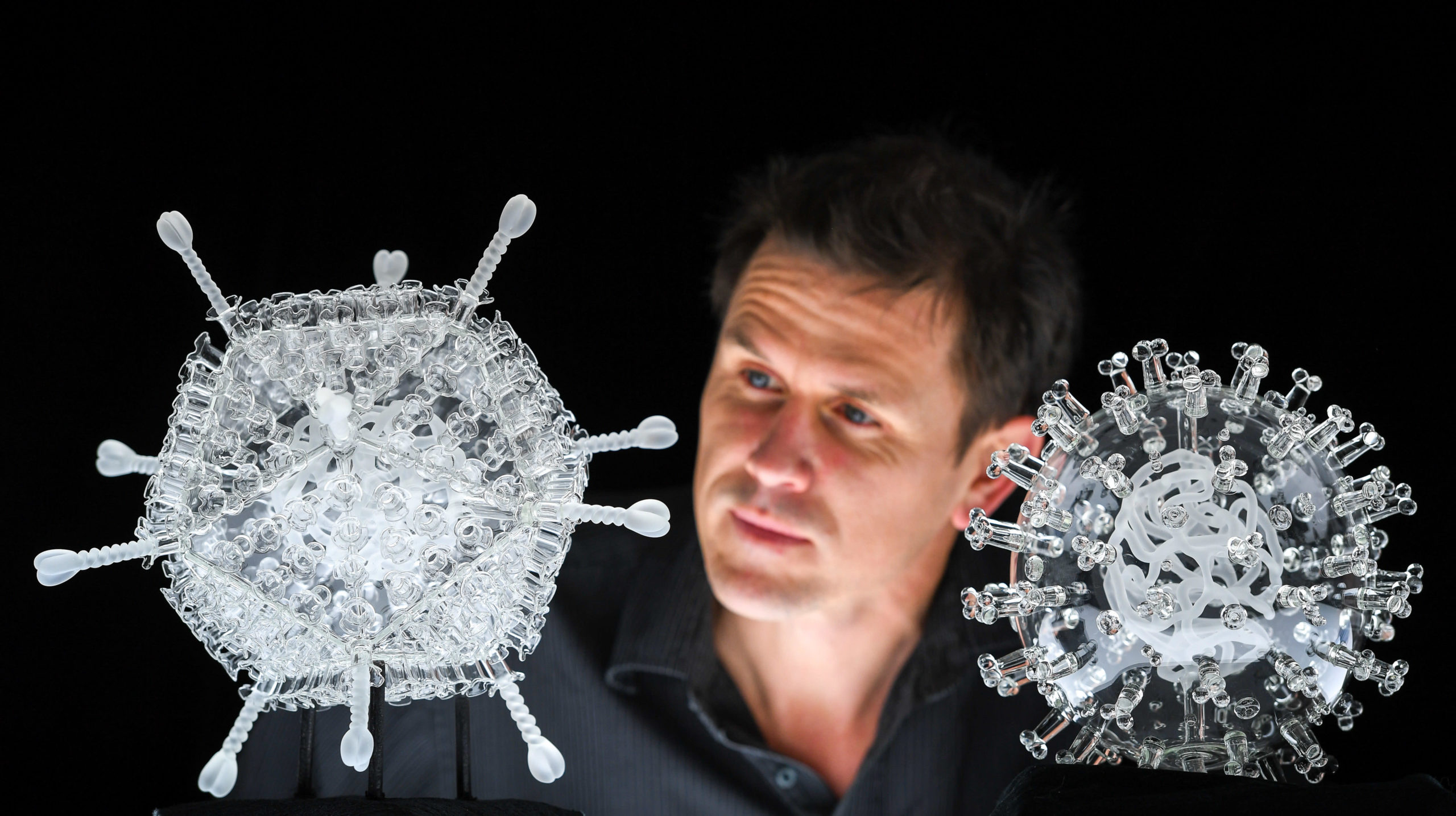 Artist Luke Jerram with his glass sculpture of the Oxford-AstraZeneca coronavirus vaccine, left, alongside his earlier work of the virus itself, in glass at the Paintworks on February 05, 2021 in Bristol, England. (Photo: Finnbarr Webster, Getty Images)