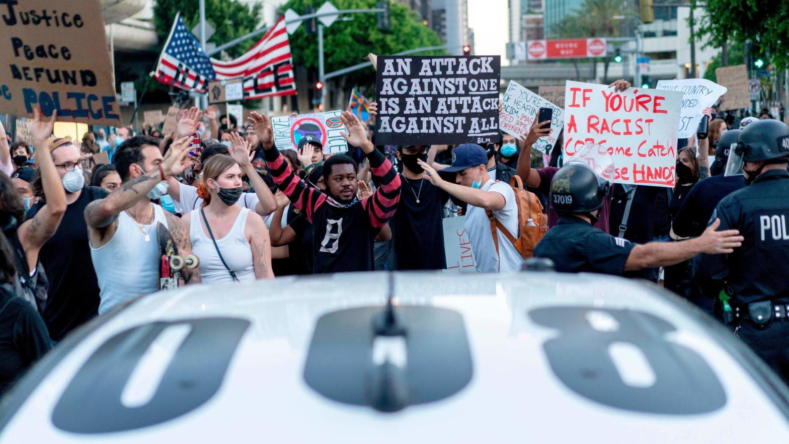 Protesters pass LAPD officers in Los Angeles on June 6, 2020. (Photo: Kyle Grillot/AFP, Getty Images)