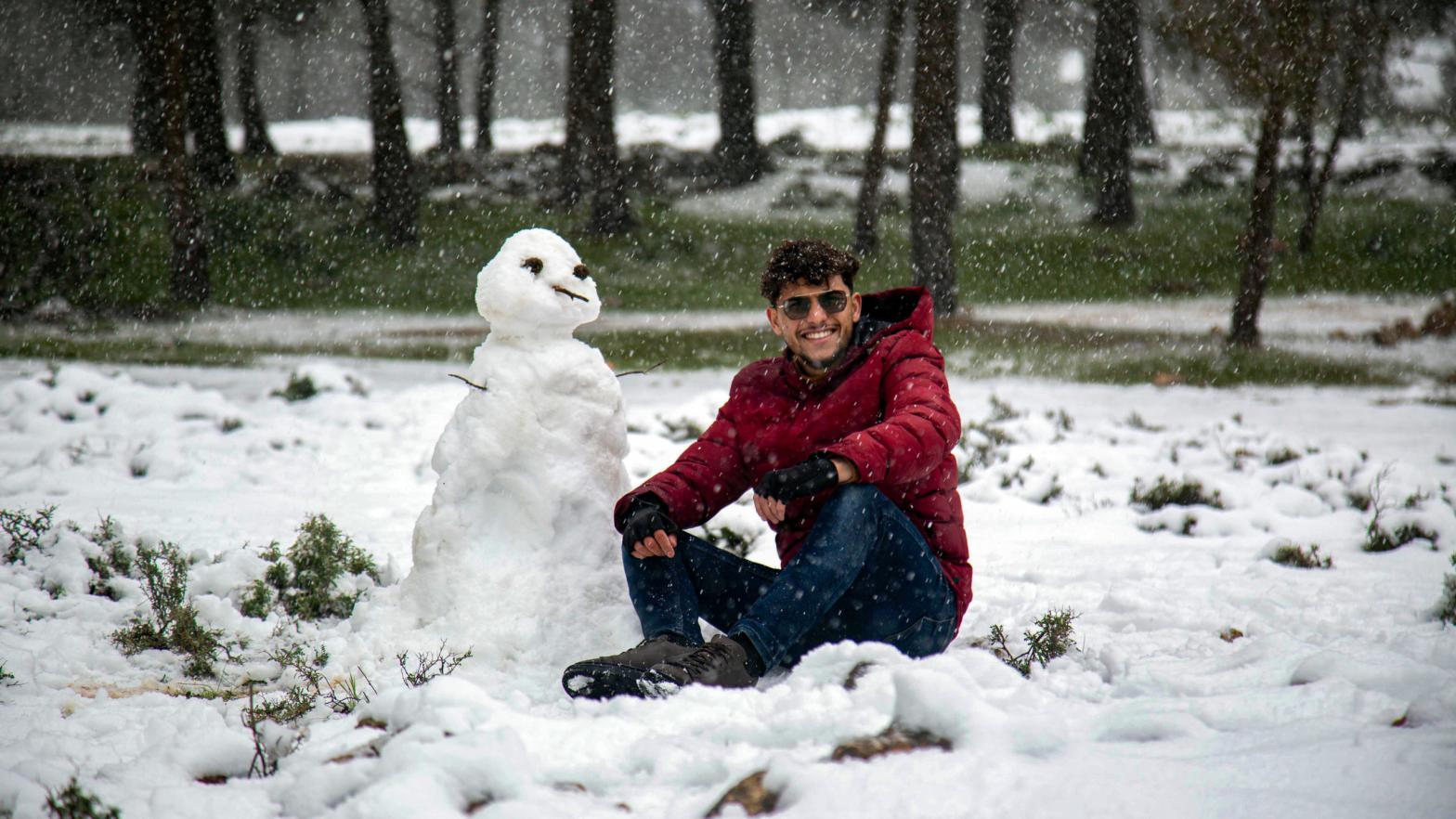 A man poses for a picture next to a snowman outside a forested area in the Sidi al-Hamri region of Libya's eastern Jebel Akhdar (Green Mountain) upland region, about 200 kilometres east of Benghazi, on February 16, 2021. (Photo: AFP via Getty Images, Getty Images)