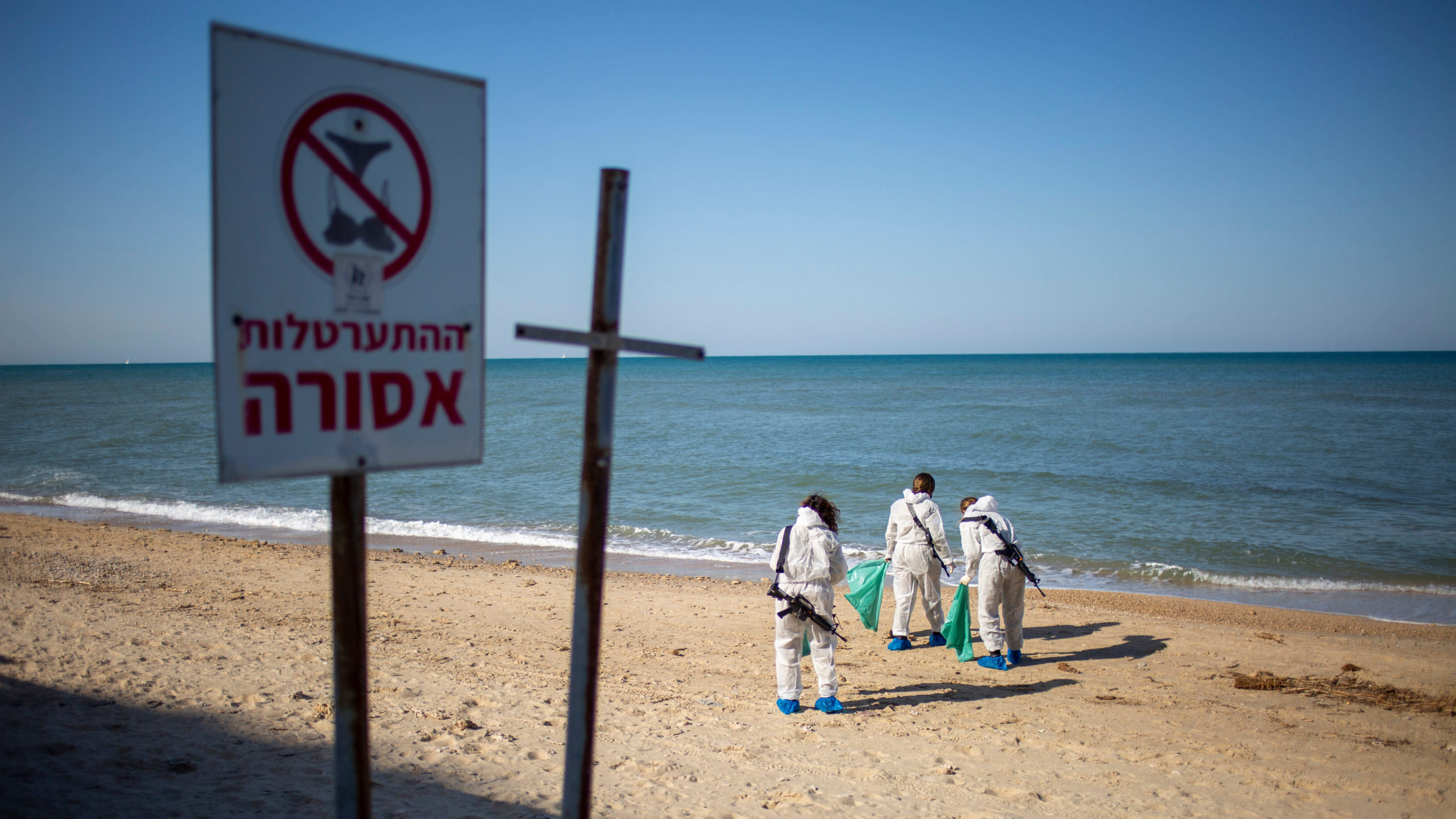 Israeli soldiers wearing protective suits clean tar from an oil spill in the Mediterranean Sea. (Photo: Ariel Schalit, AP)
