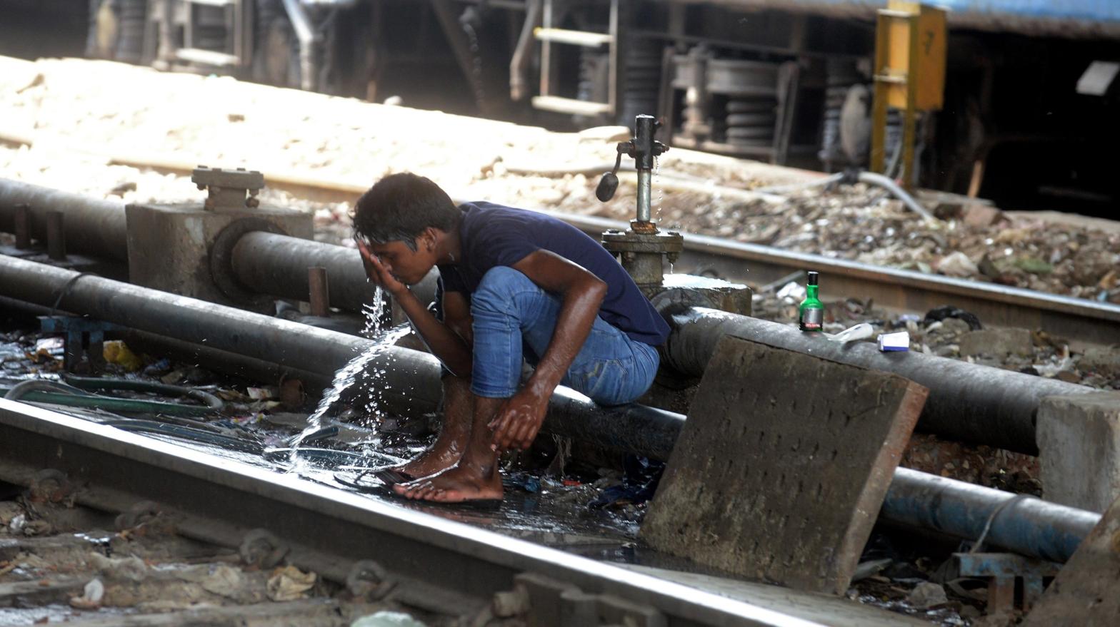 A man washes himself at a water pipe to cool down along the railway tracks in New Delhi. (Photo: RAVEENDRAN/AFP, Getty Images)