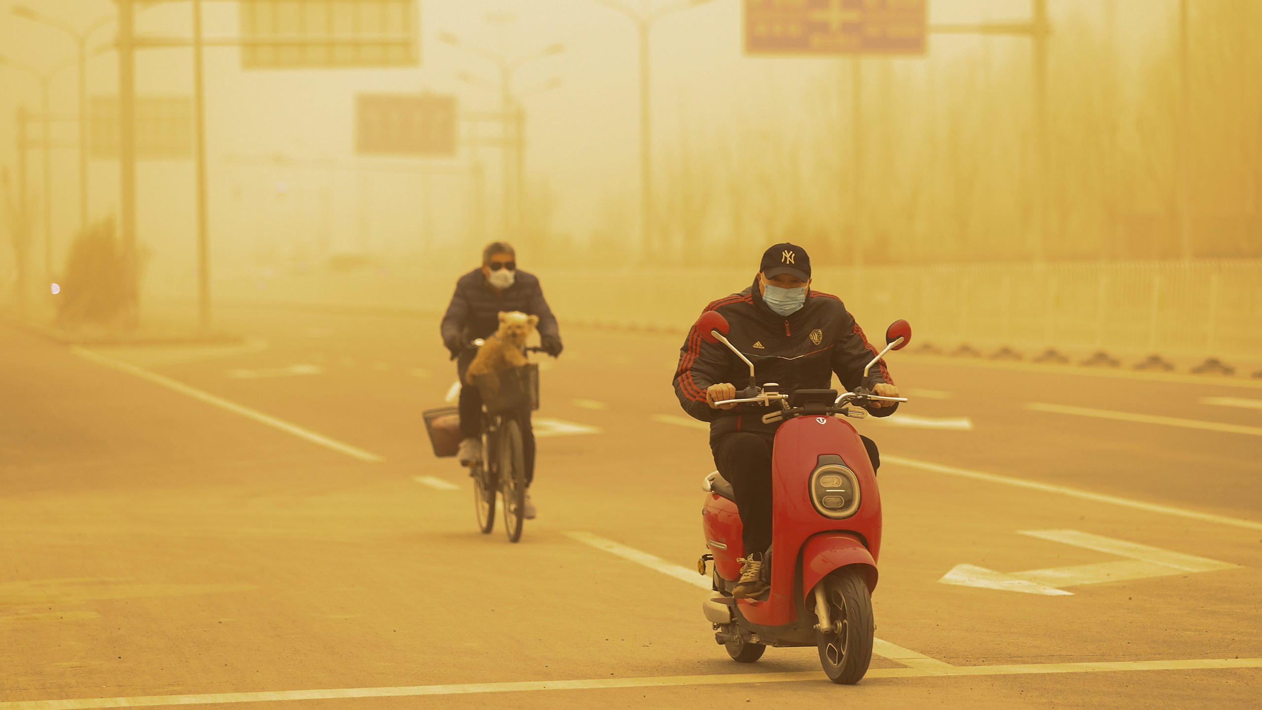 People wearing protective masks ride their bikes along a street during a sandstorm on March 15, 2021 in Beijing, China. The Chinese capital and the northern parts of the country was hit with a sandstorm on Monday, sending air quality indexes of PM 2.5 and PM 10 ratings into the thousands and cancelling flights. (Photo: Getty, Getty Images)