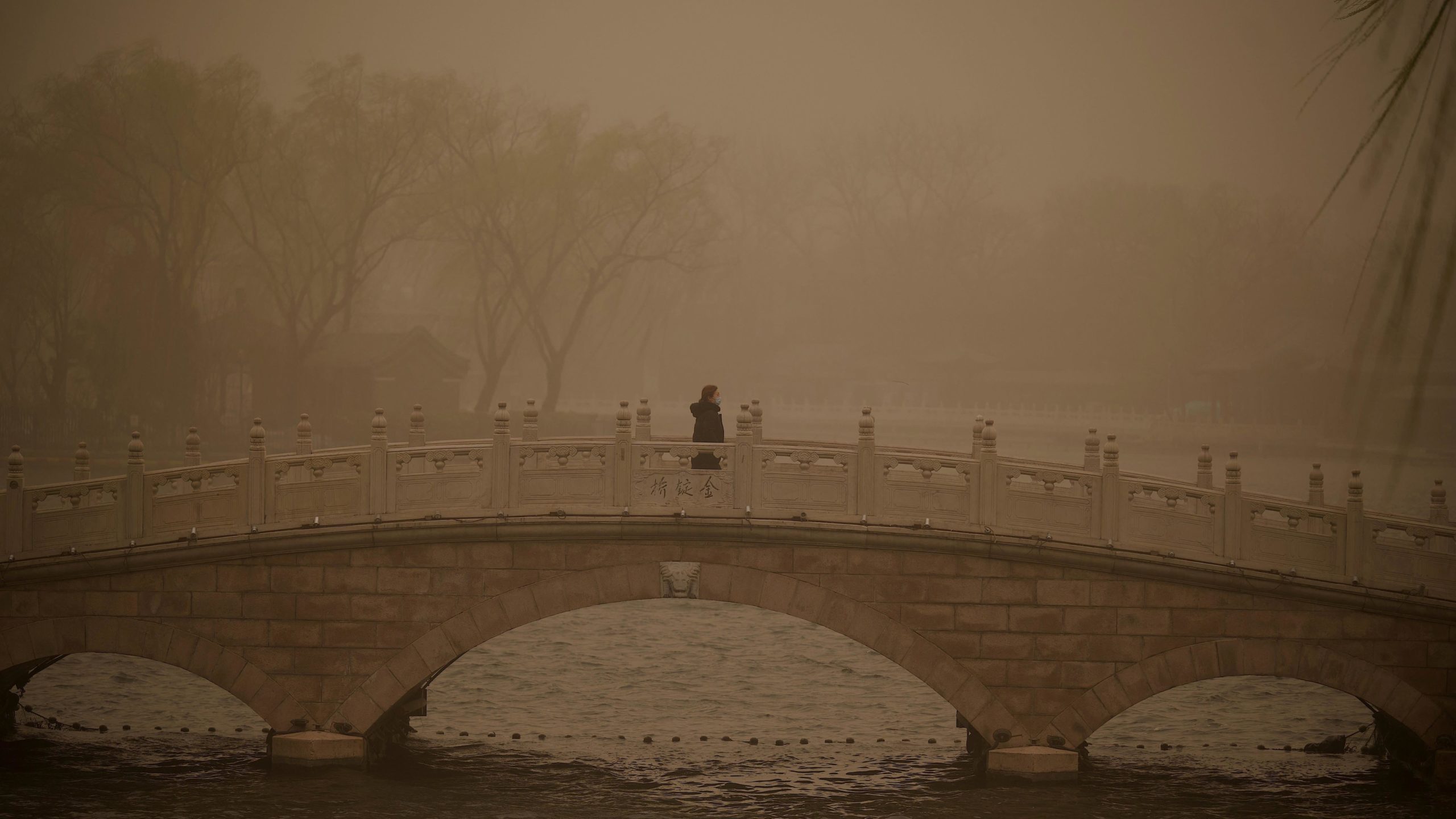 A woman crosses a bridge at Houhai lake during a sandstorm in Beijing on March 15, 2021.  (Photo: Noel Celis, Getty Images)