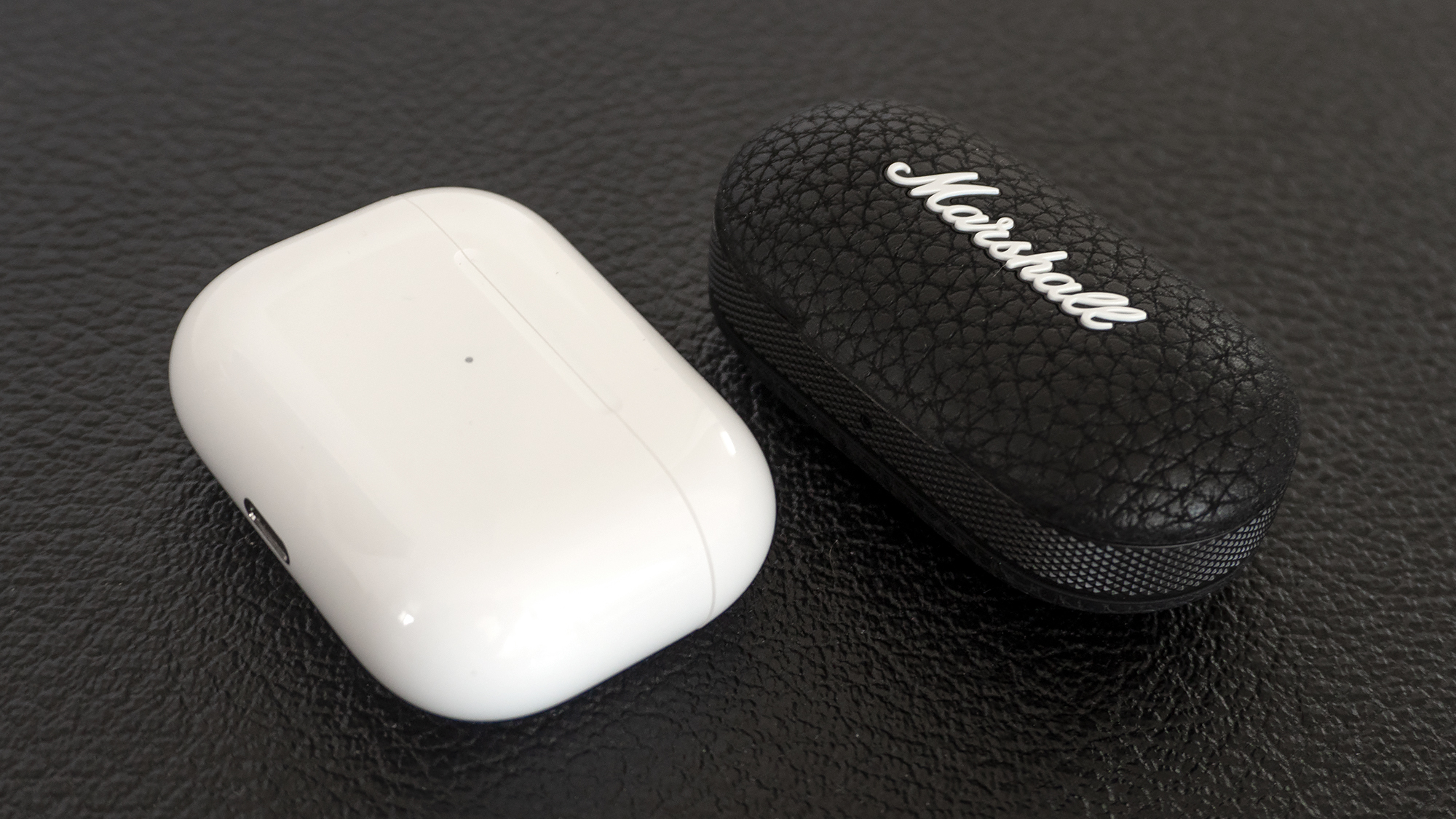 It's a toss-up between the AirPods Pro (left) and the Marshall Mode II (right) as to which set of wireless earbuds has the smaller charging case. (Photo: Andrew Liszewski - Gizmodo)