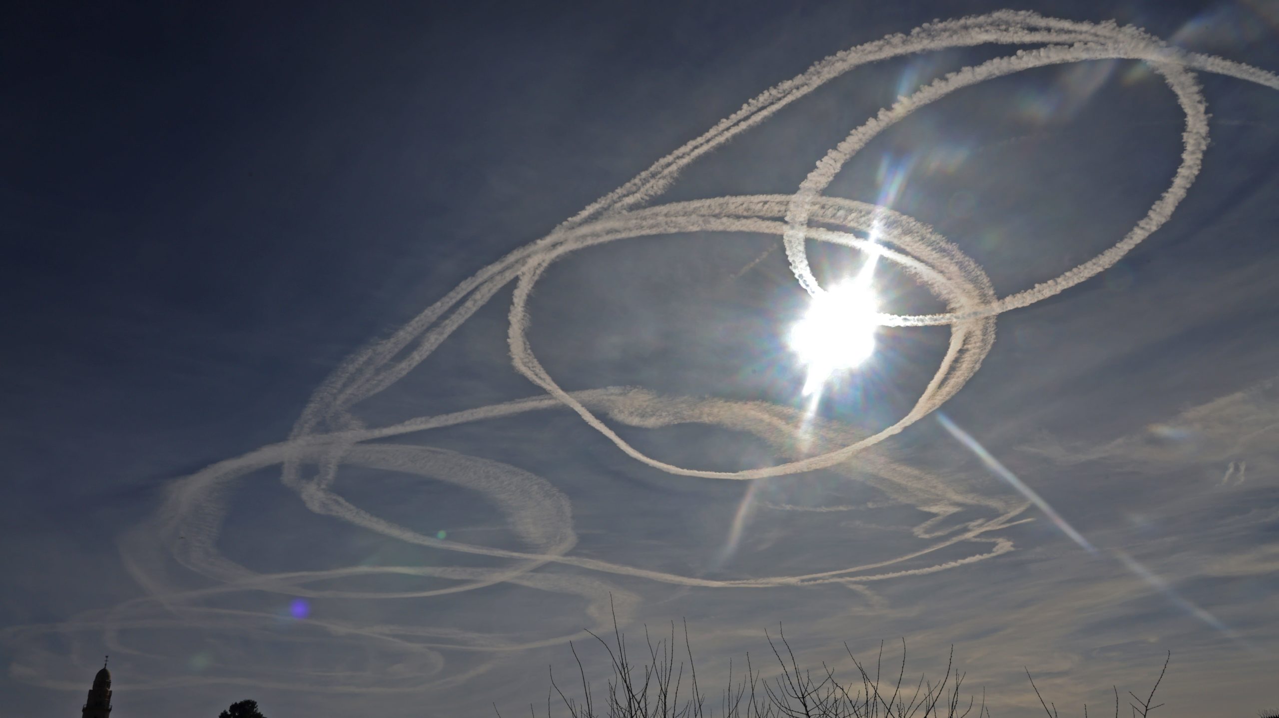 Aircraft contrails circle the sun above the Old City of Jerusalem on January 26, 2021.  (Photo: Emmanuel Dunand / AFP, Getty Images)
