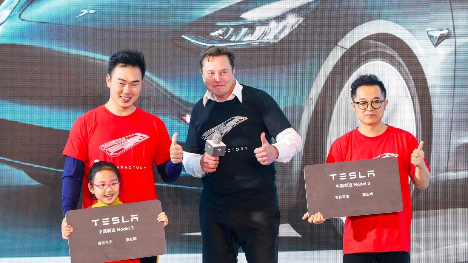 Elon Musk poses for photos with buyers during the Tesla China-made Model 3 Delivery Ceremony in Shanghai. (Photo: STR / AFP, Getty Images)