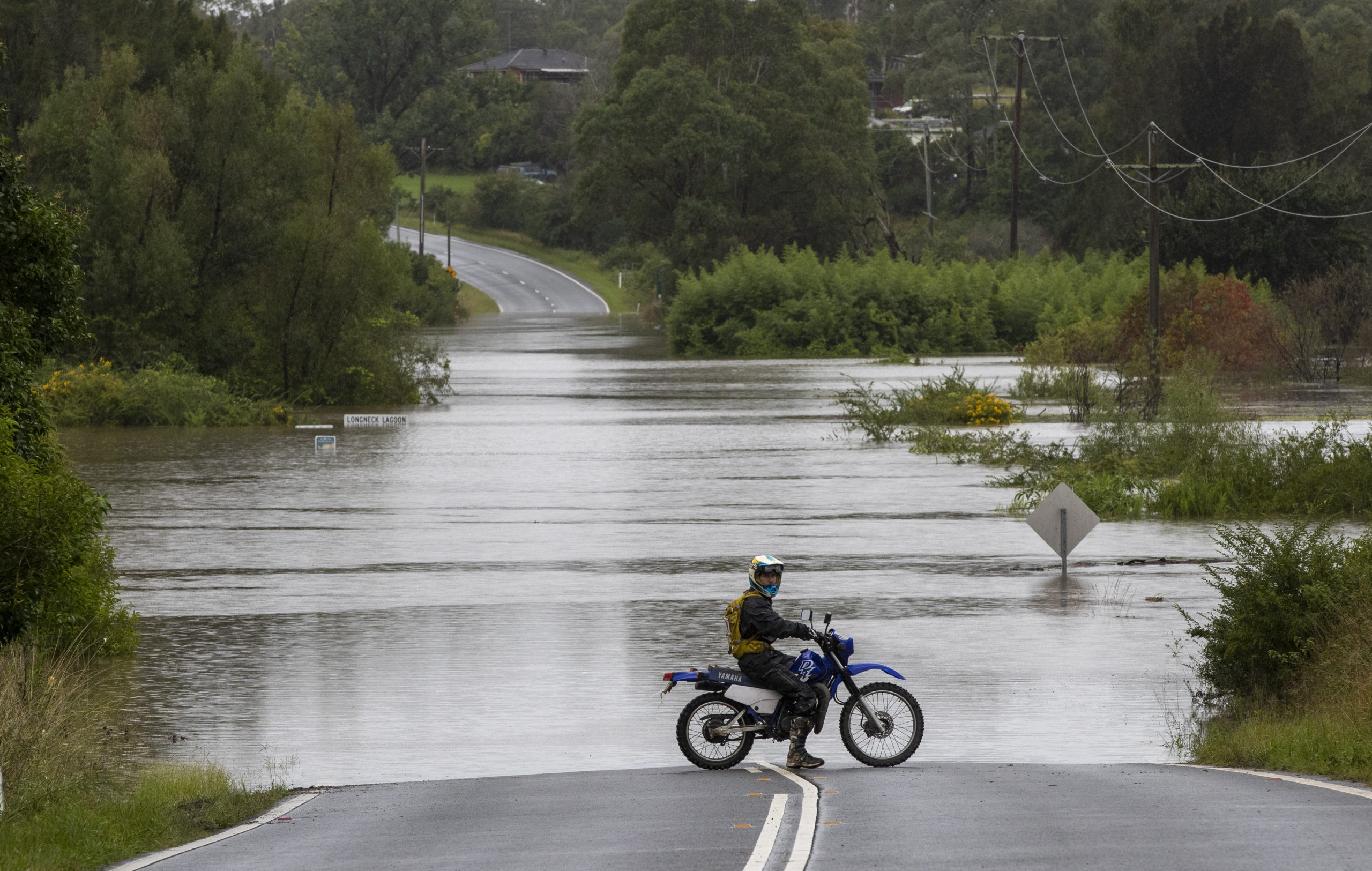 A motorcyclist's progress is blocked by a flooded road at Old Pitt Town, northwest of Sydney. (Photo: Mark Baker, AP)