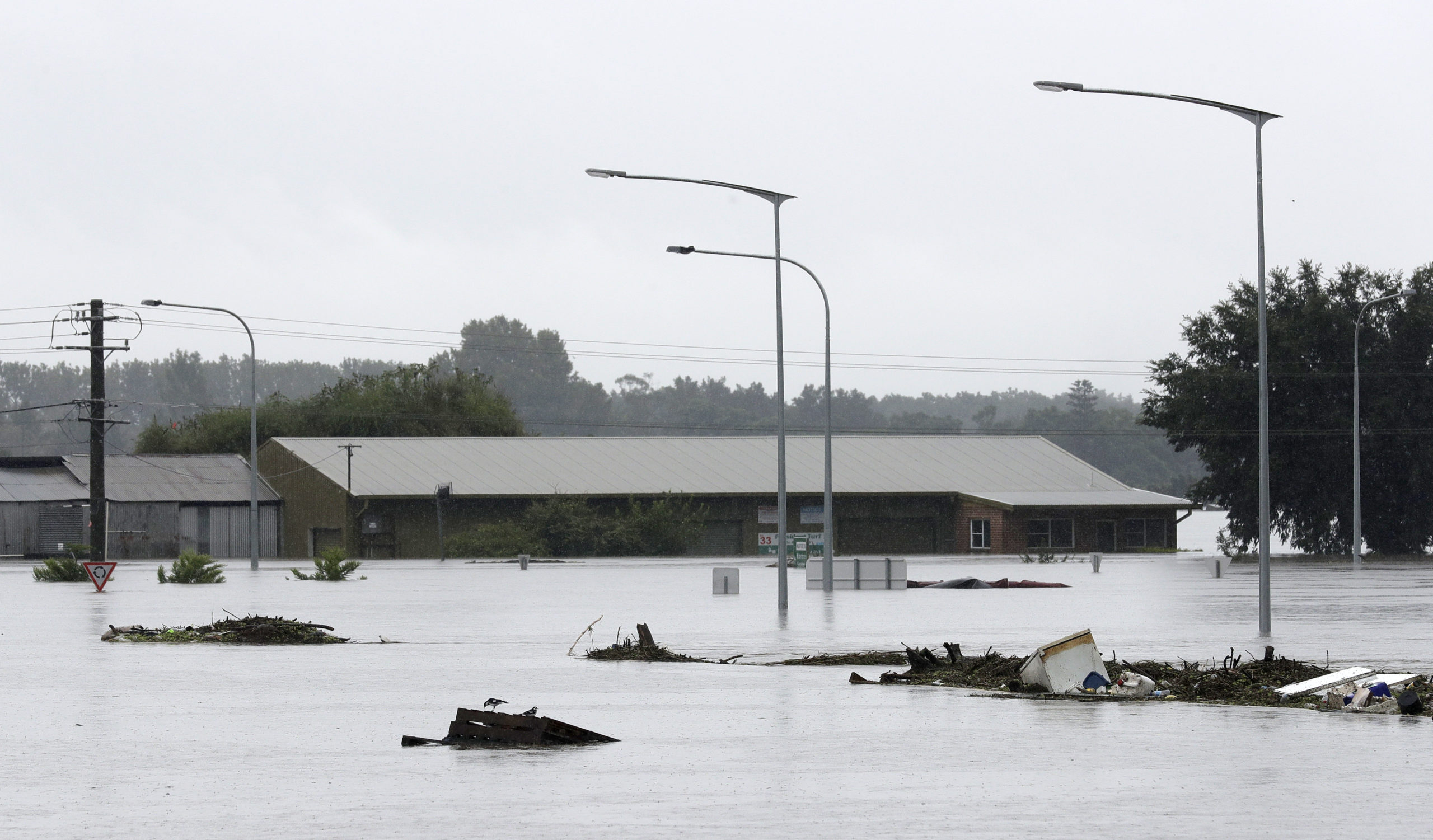 Debris floats past a partially submerged business flooded by water from the Hawkesbury River in Windsor, northwest of Sydney. (Photo: Rick Rycroft, AP)