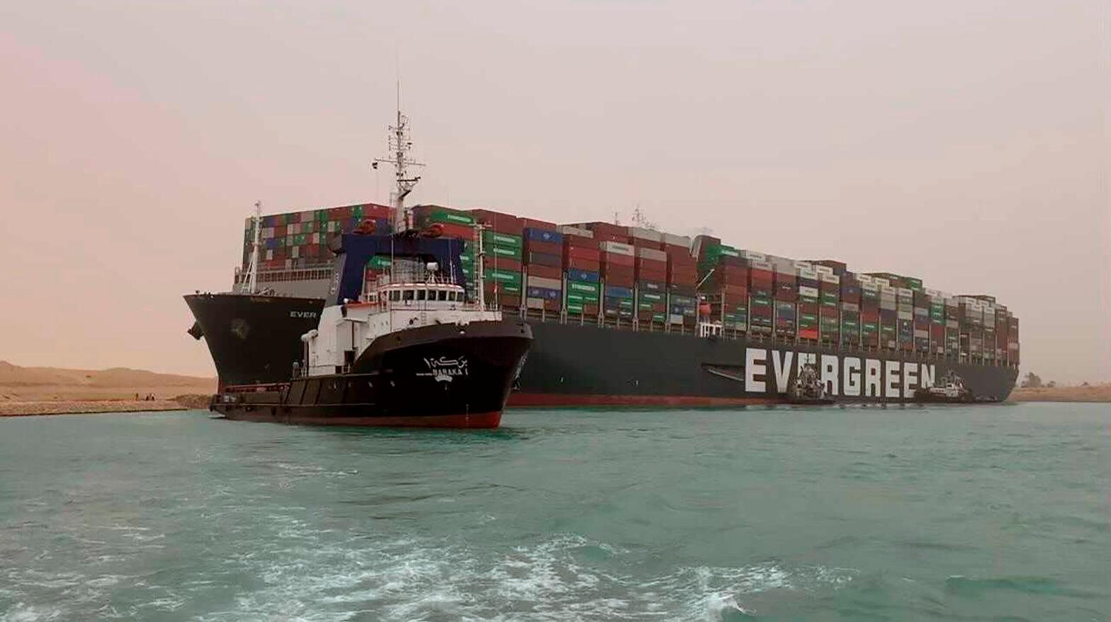 A boat navigates in front of the Ever Green, which turned sideways in Egypt's Suez Canal, blocking traffic in a crucial East-West waterway for global shipping. (Photo: Suez Canal Authority, AP)