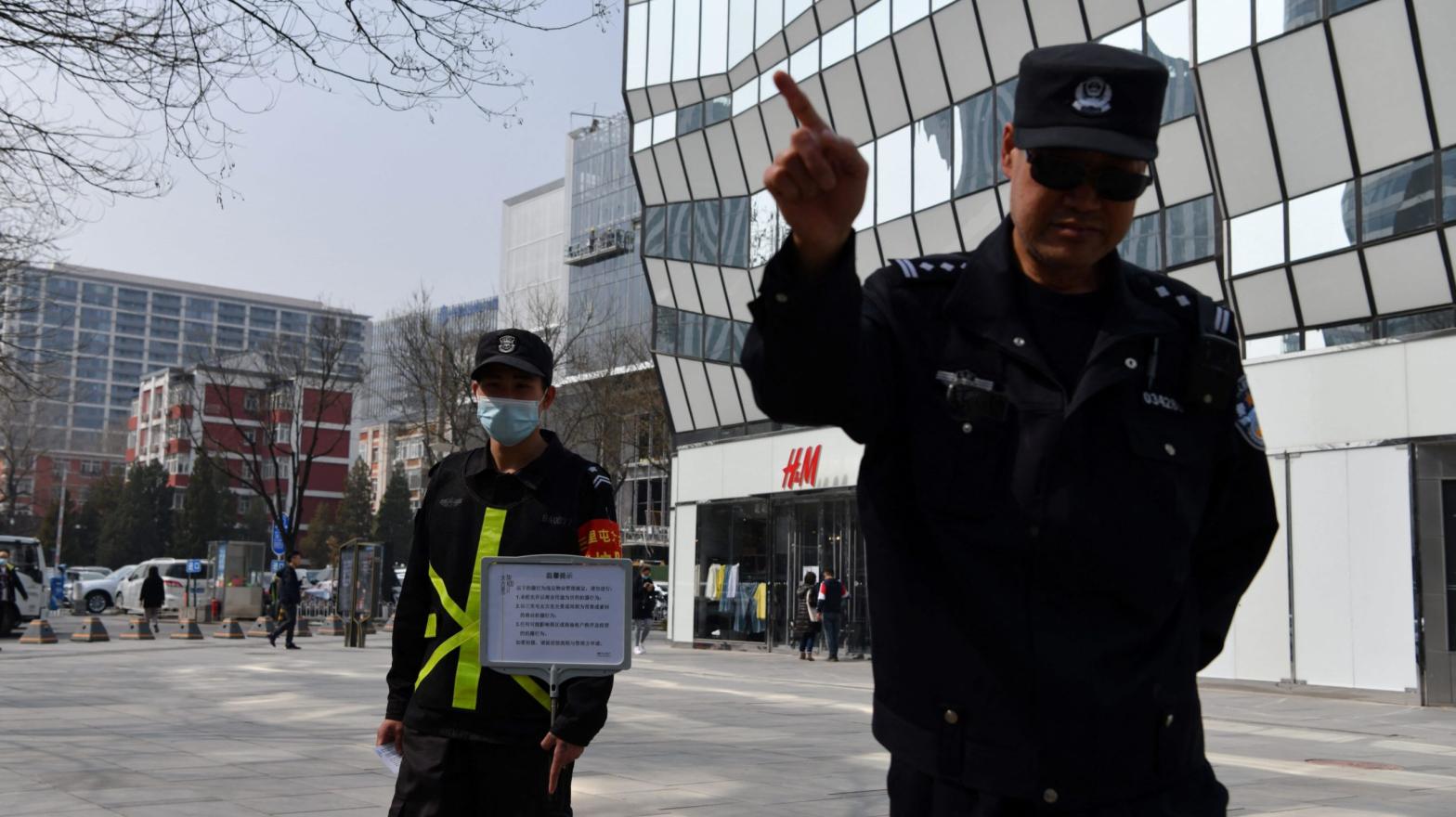 A cop tries to prevent photos from being taken outside an H&M store in Beijing on March 25, 2021. (Photo: Greg Baker/AFP, Getty Images)