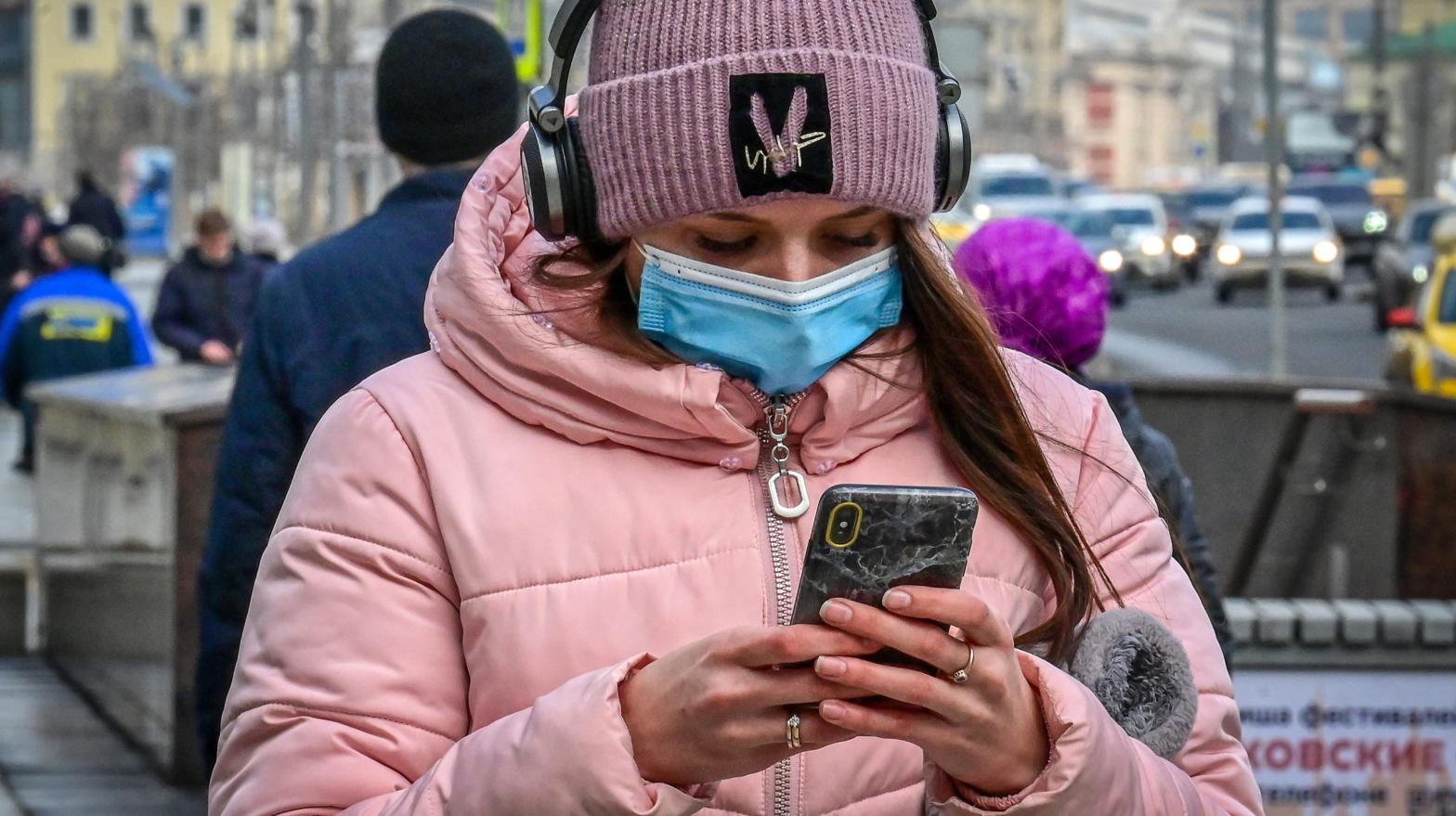 A woman wearing a face mask to protect against the coronavirus disease uses her smartphone walking on a street in Moscow on March 19, 2021.  (Photo: Yuri Kadobnov, Getty Images)