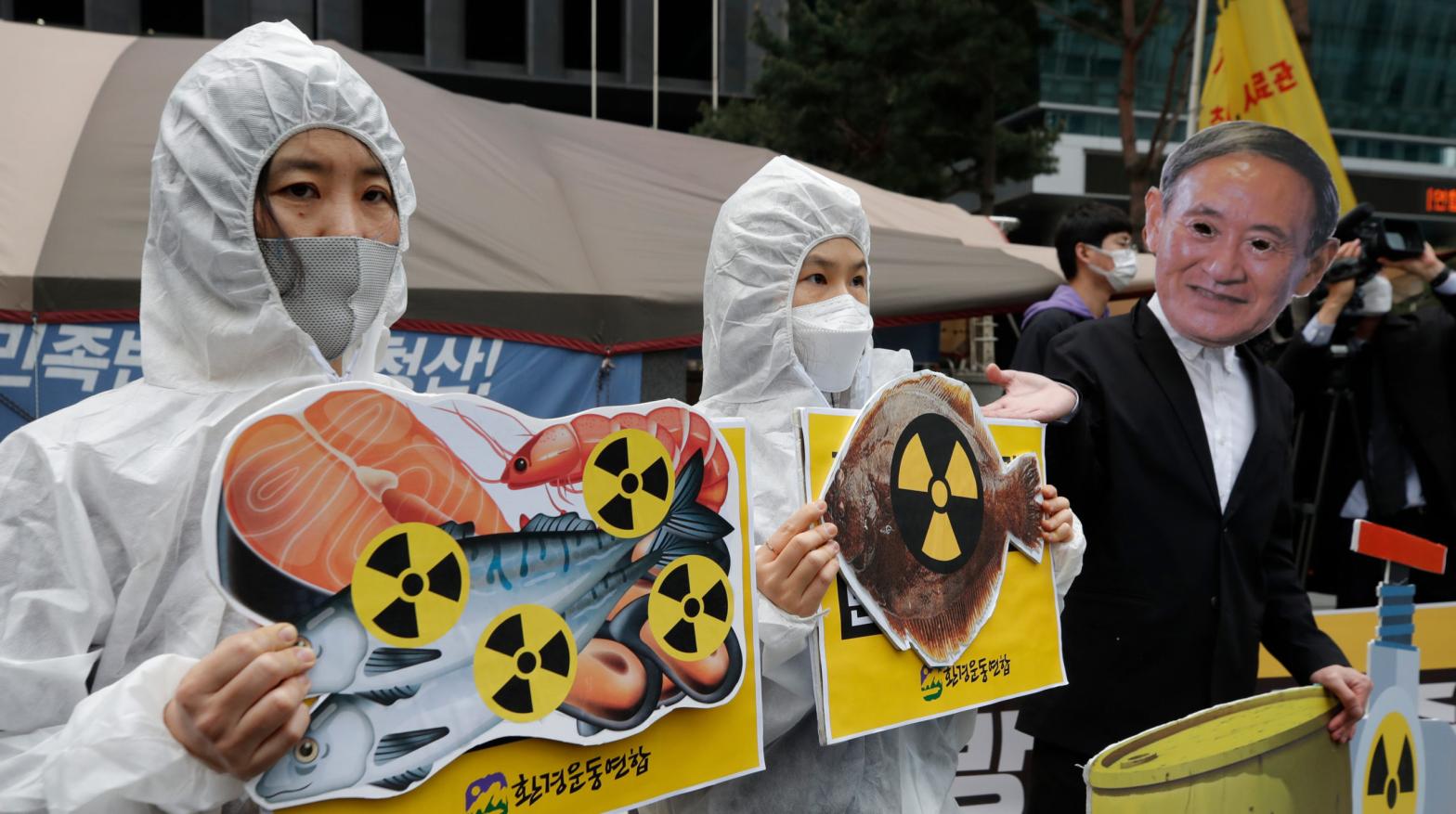 Environmental activists wearing a mask of Japanese Prime Minister Yoshihide Suga and protective suits protest the government's decision in Seoul, South Korea. (Photo: Lee Jin-man, AP)